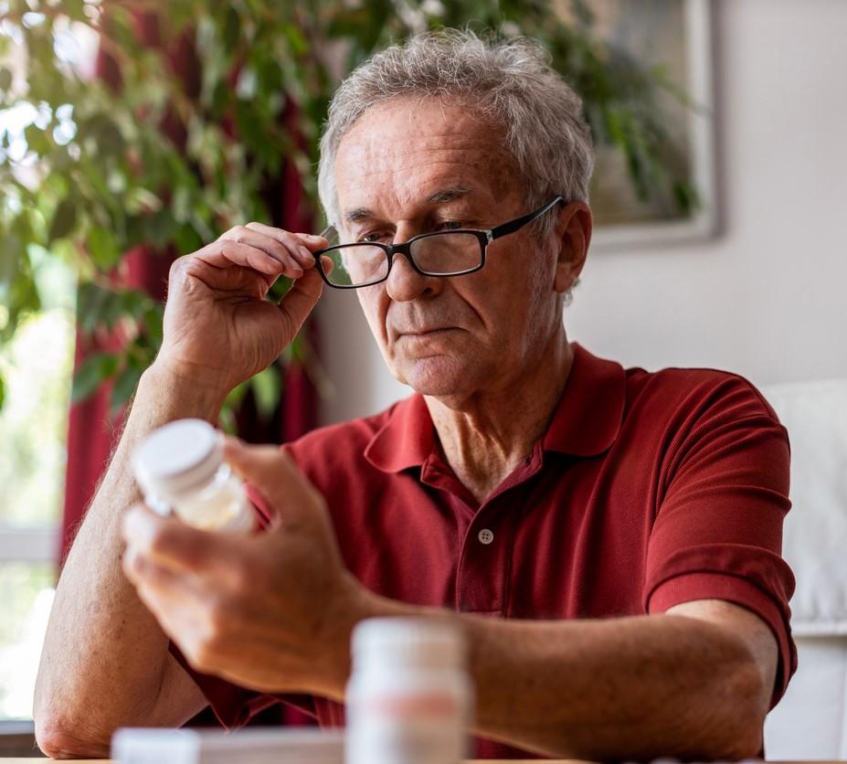 Older man reading pill bottle instructions