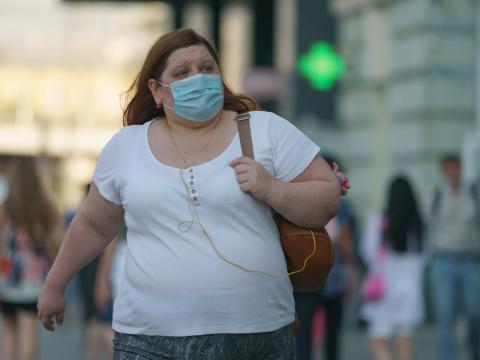 Woman with obesity walking down street with mask on