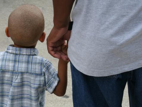 Back view of little boy holding his dad's hand