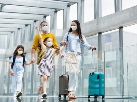 Mask-wearing family with luggage in airport