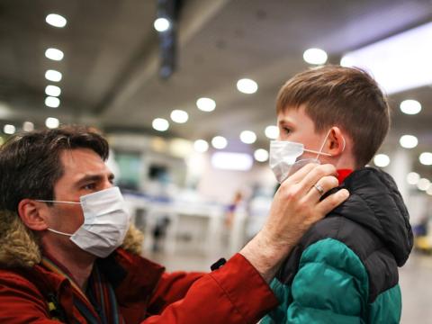 Father and son putting masks on in airport
