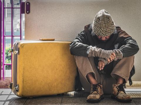 Dejected homeless man sitting on sidewalk