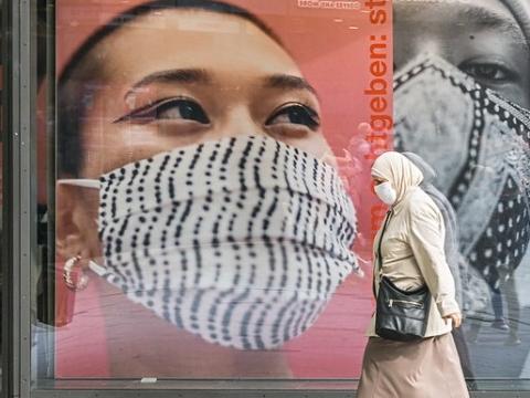 Masked woman walking in front of masking signs