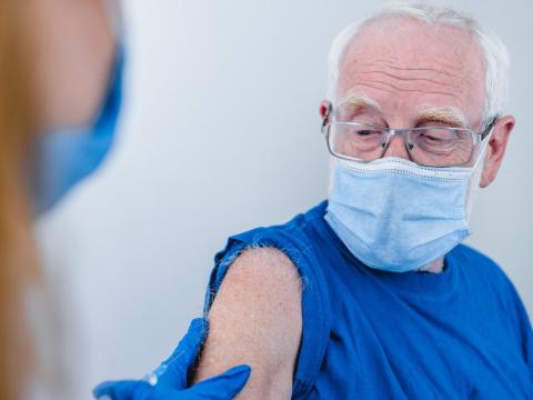 Older man in mask getting vaccinated