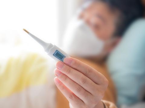Sick man in bed reading thermometer