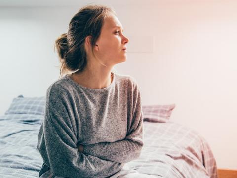Suffering woman sitting on bed