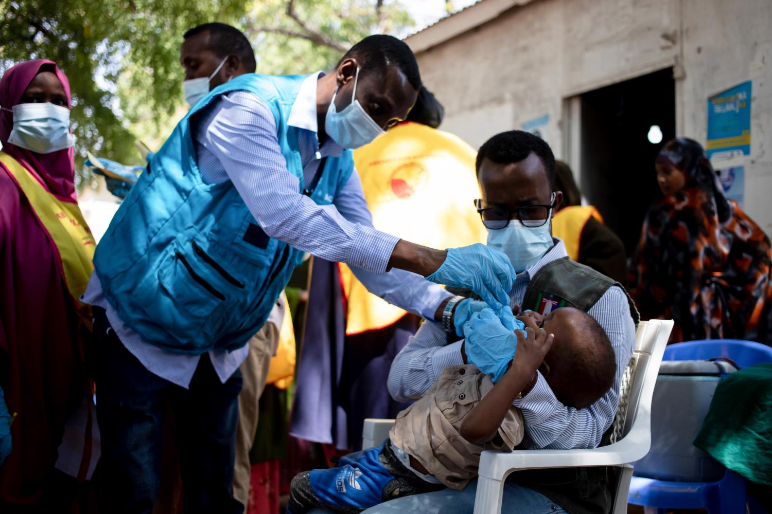 Health workers administering vaccine to infant in Africa