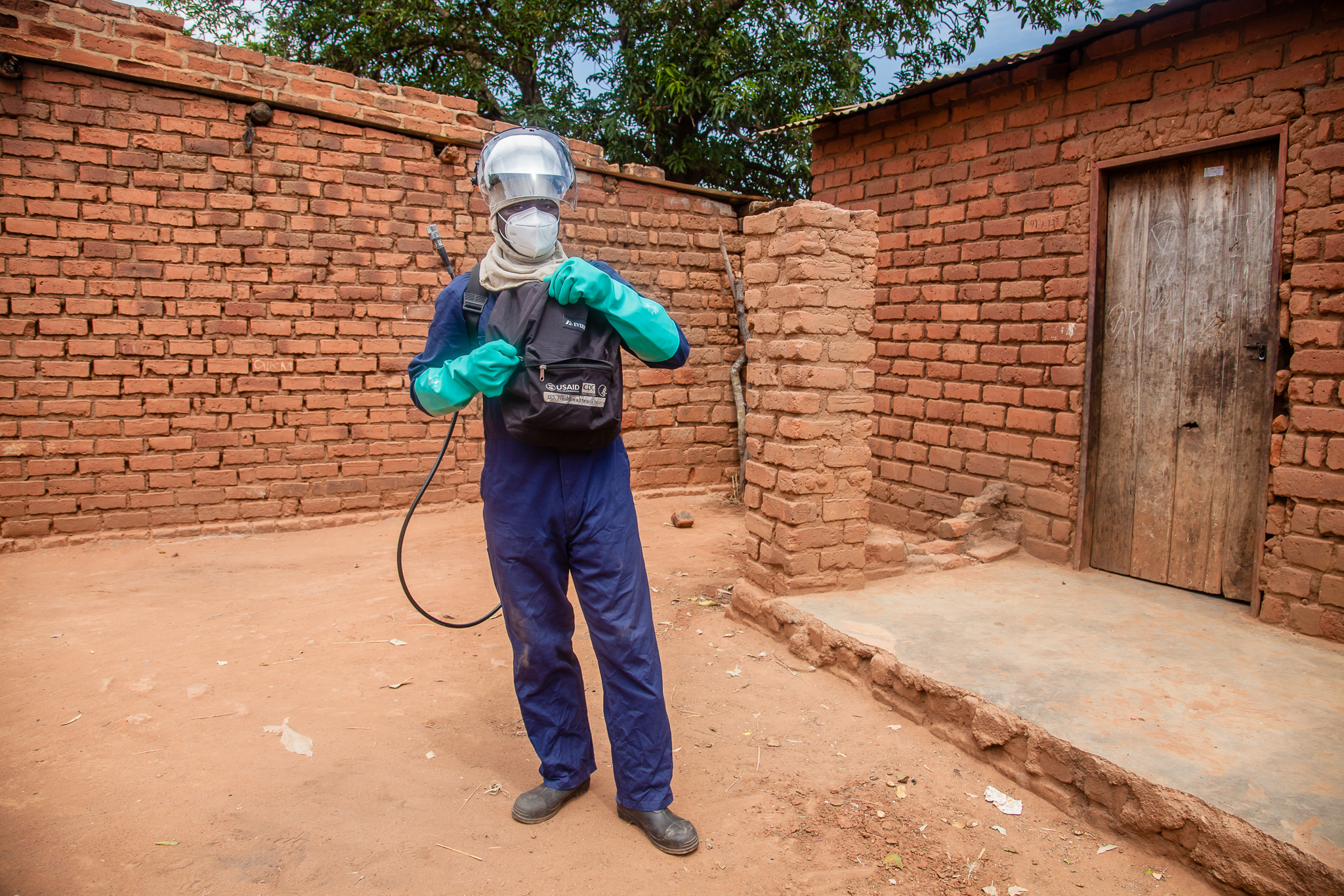 USAID worker in Zambia spray homes with insecticide to protect against malaria.
