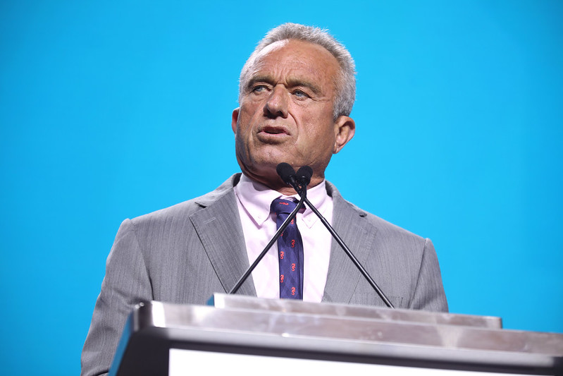 Robert F. Kennedy Jr. in front of a lectern with a blue background behind him