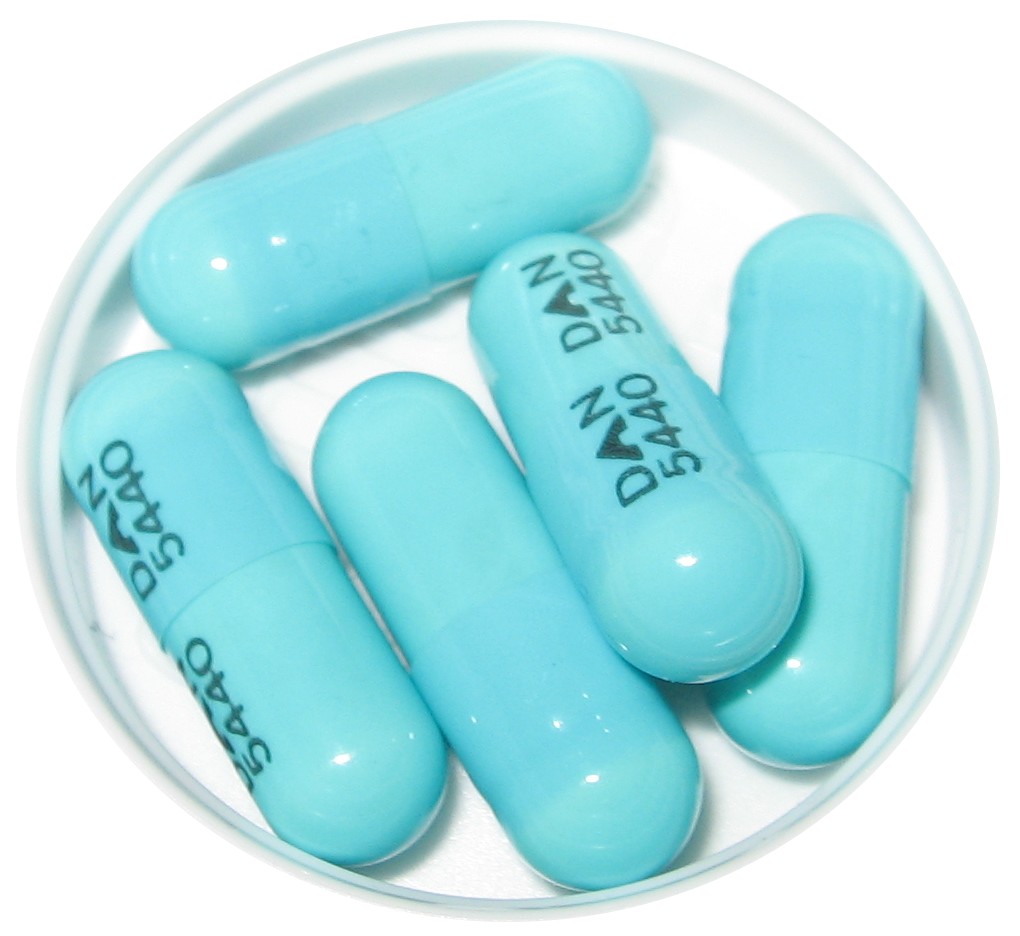 A white dish holding five light blue doxycycline capsules, 100 mg each.