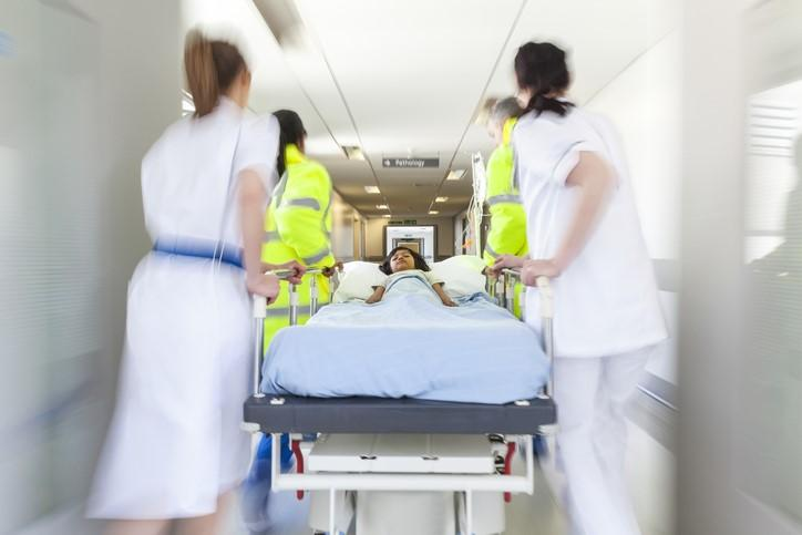 Clinicians rushing patient through hall in hospital