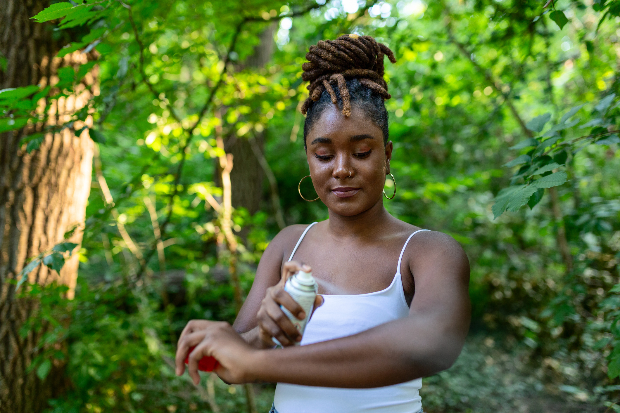 A woman sprays herself with insect repellent.