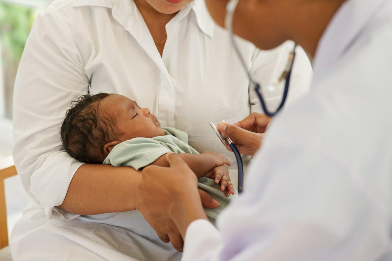 Infant in mom's arms with doctor
