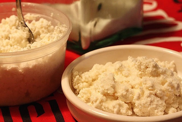 Requeson cheese in bowl and plastic container on table