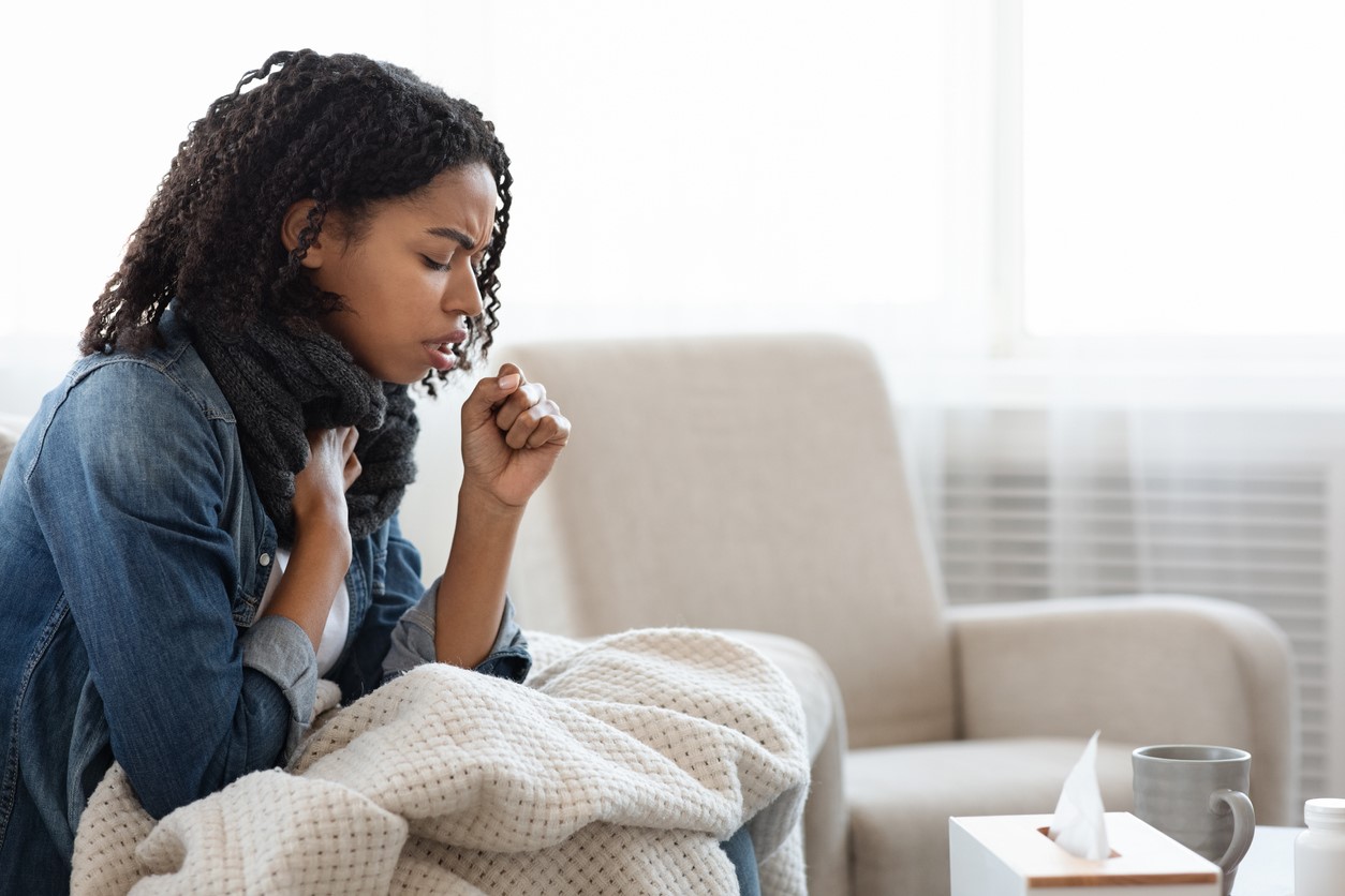 woman coughing on couch