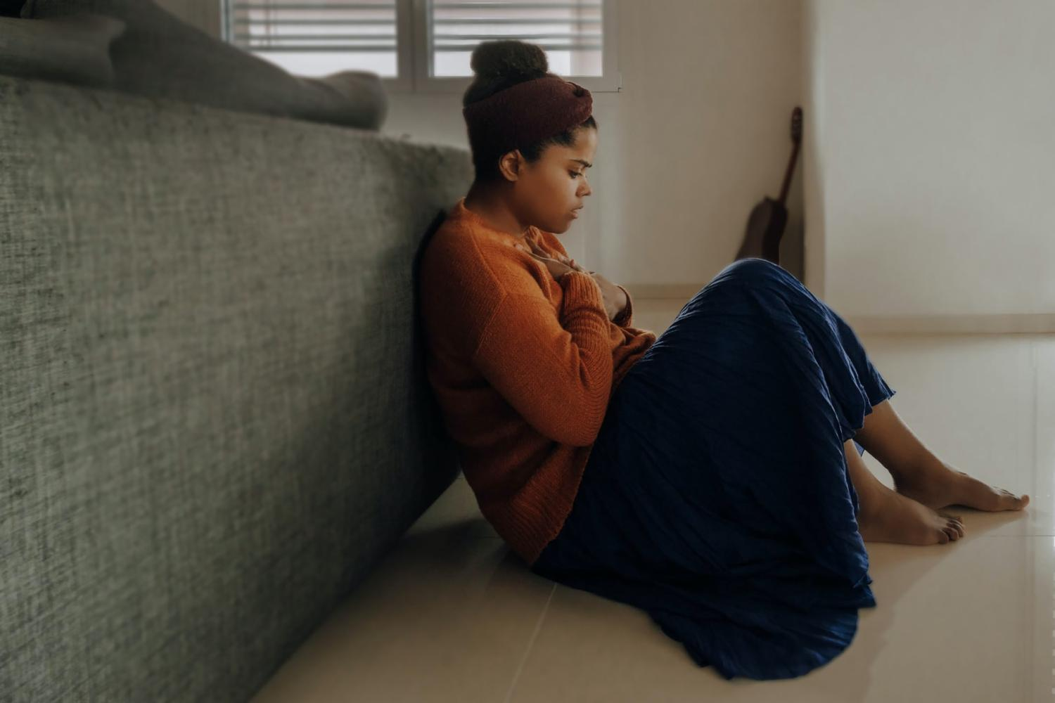 Anxious young woman sitting on floor