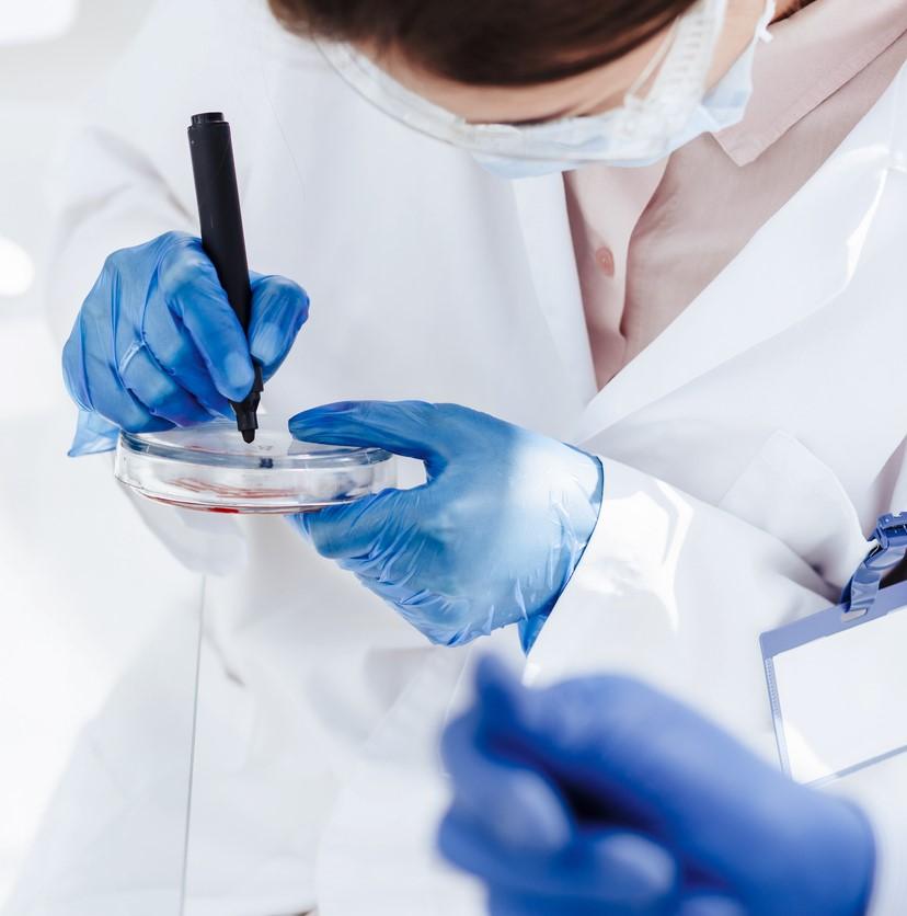 Scientist in white lab coat holding a petri dish