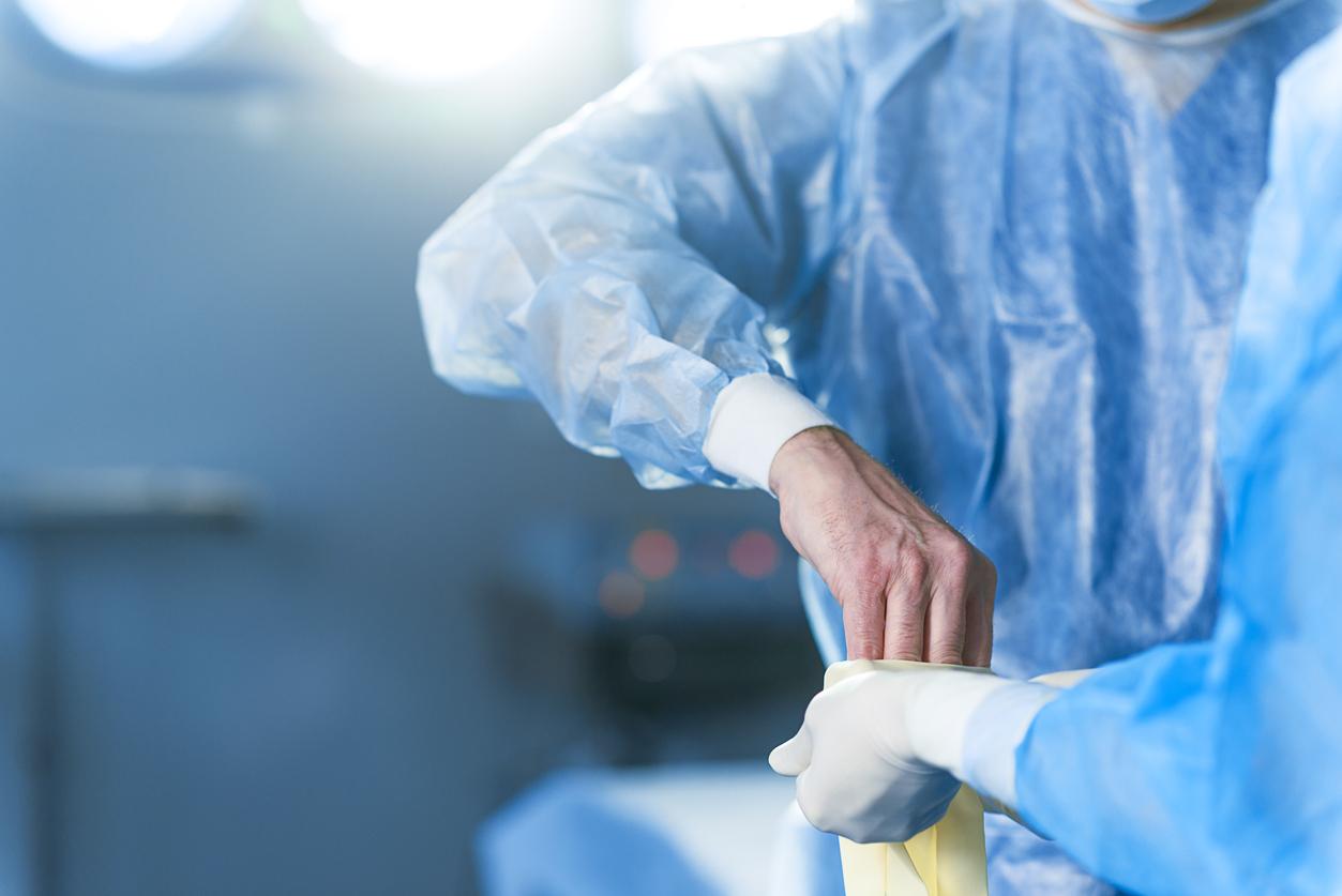 Nurse donning gloves and gown