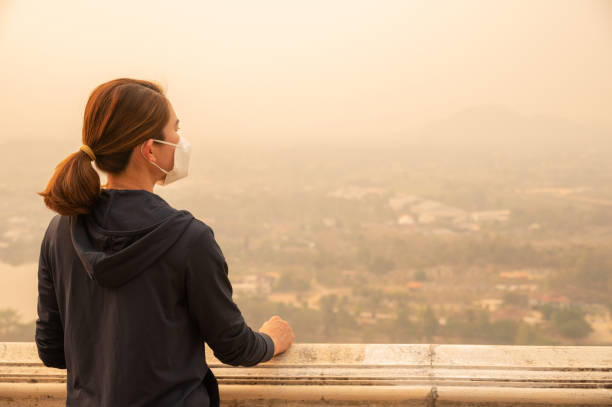 Woman with N95 overlooking polluted city