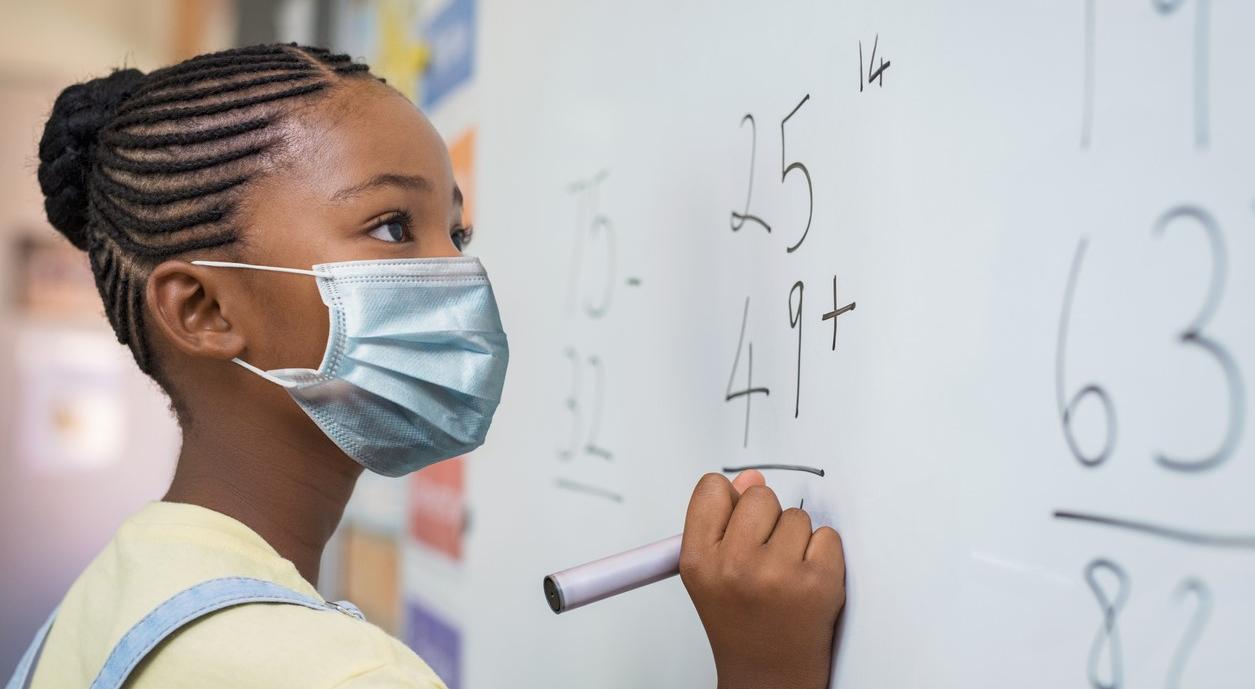 Schoolgirl wearing mask at whiteboard