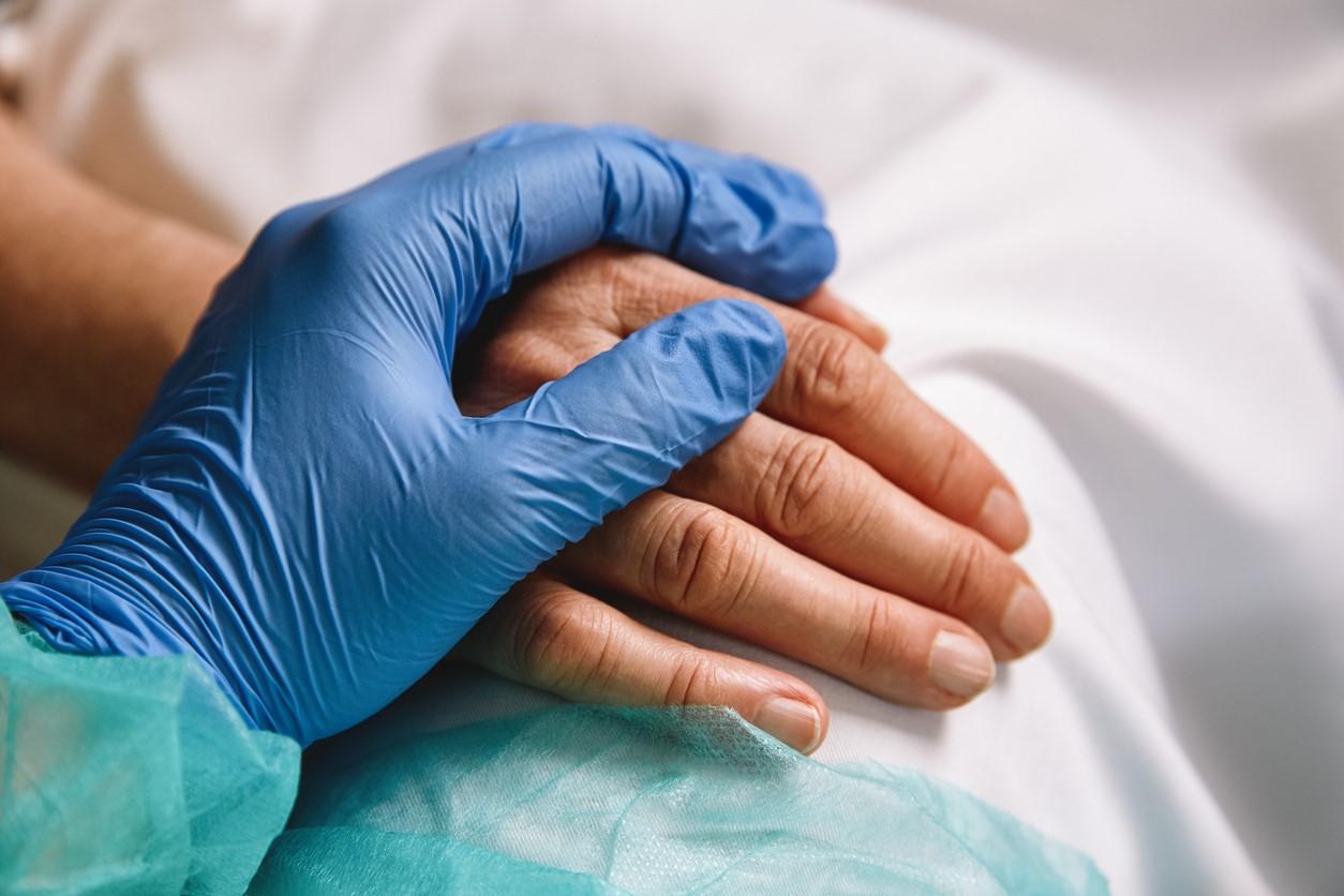 Gloved hand holding patient's hand