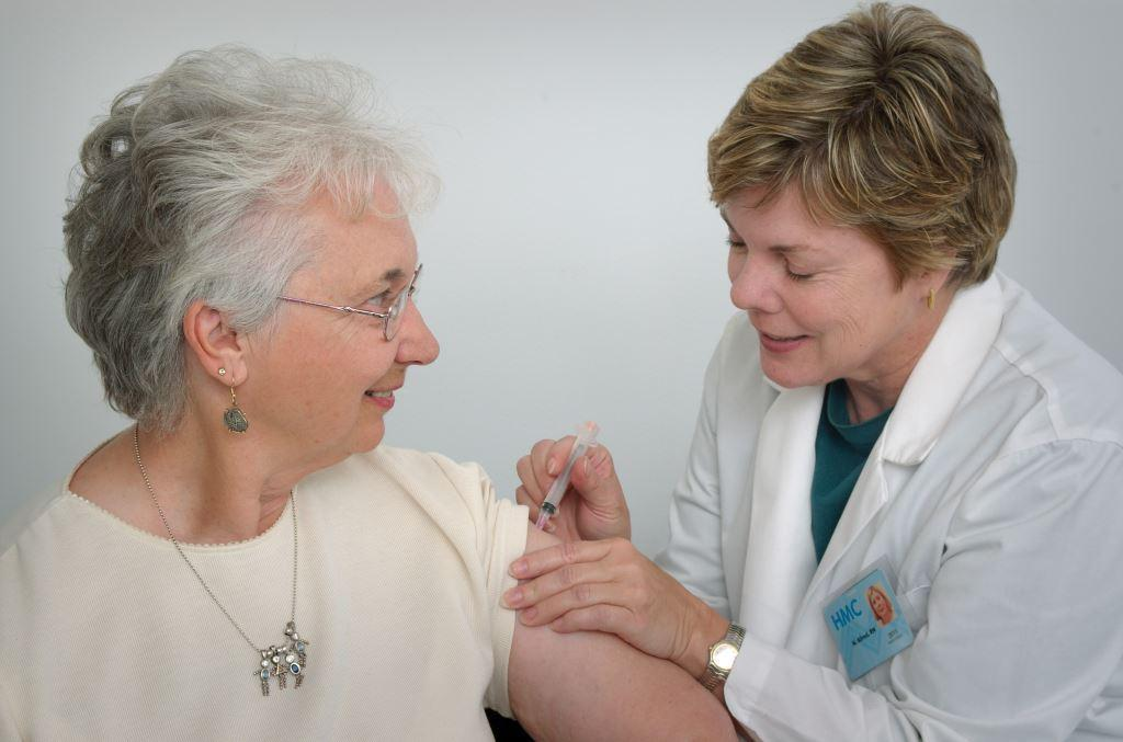 Nurse vaccinating older woman