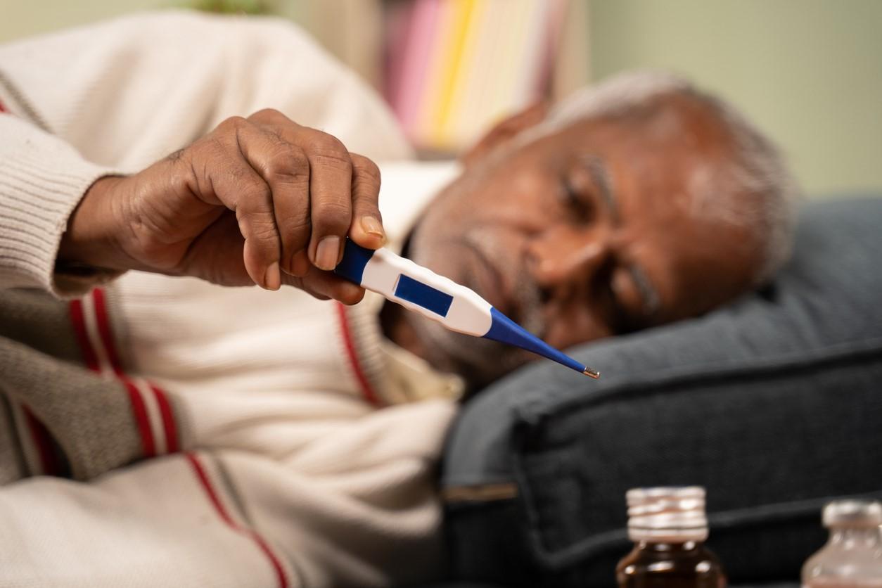 Older man in bed checking temp