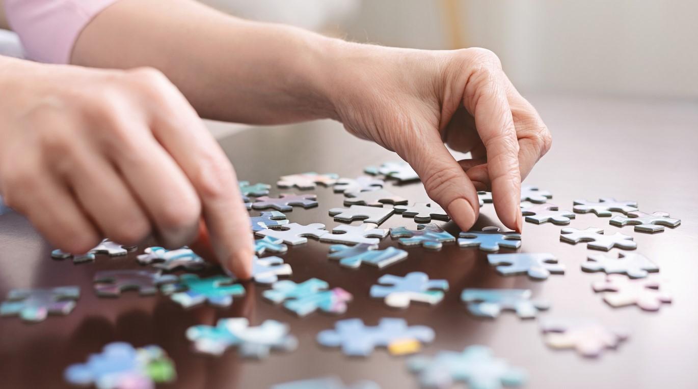 Pair of hands working jigsaw puzzle