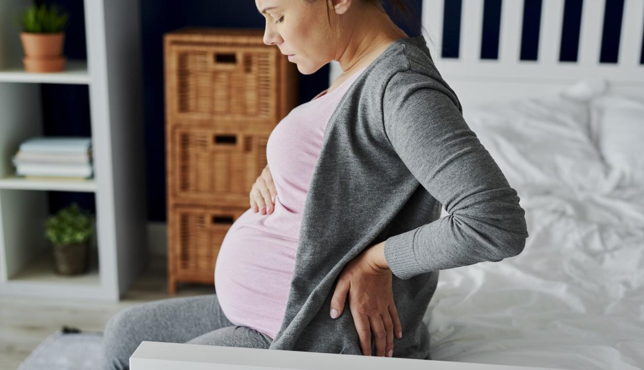 Pregnant woman sitting on bed