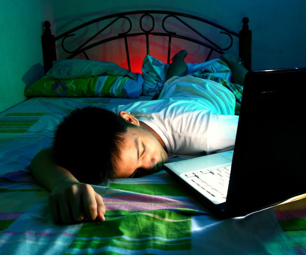 Teen boy asleep on bed with laptop