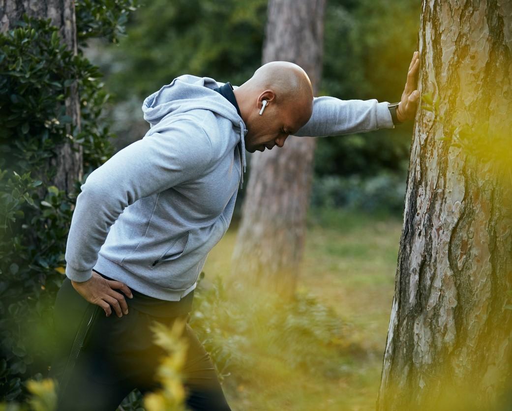 Tired man leaning on tree