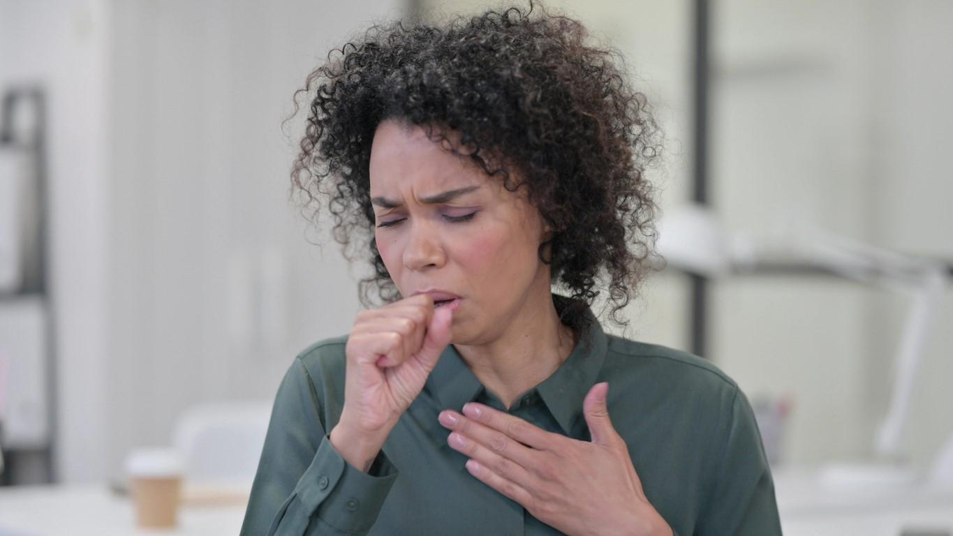 Woman coughing with hand on chest