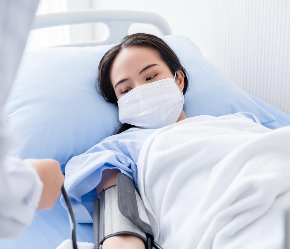 Woman in hospital bed getting blood pressure checked