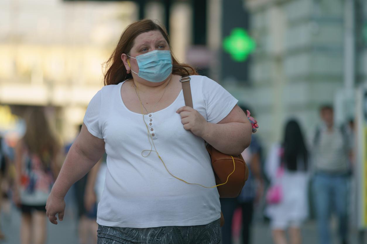 Woman with obesity walking down street with mask on