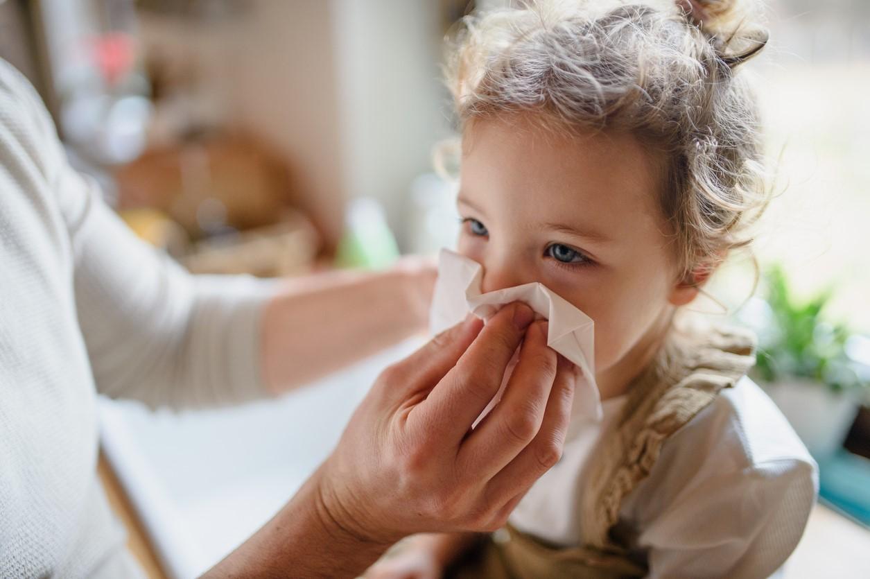 Young girl blowing nose