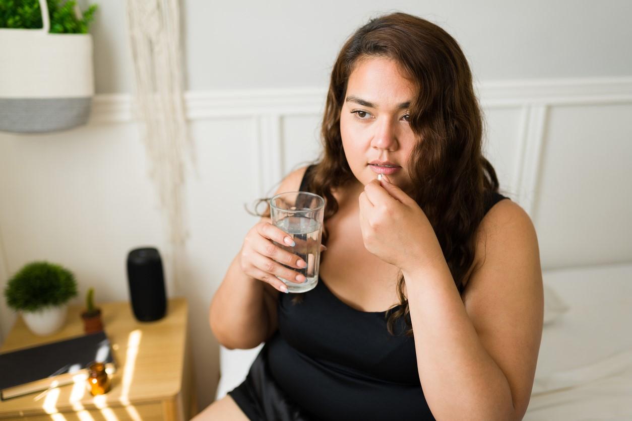 Young woman taking white pill