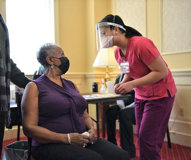 Young woman vaccinating older woman