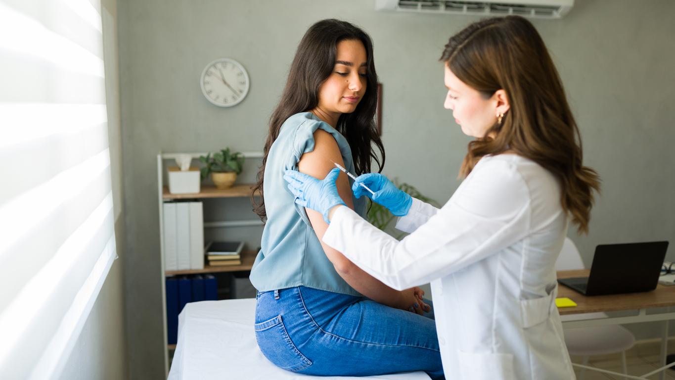 Young woman receiving a flu shot from female doctor
