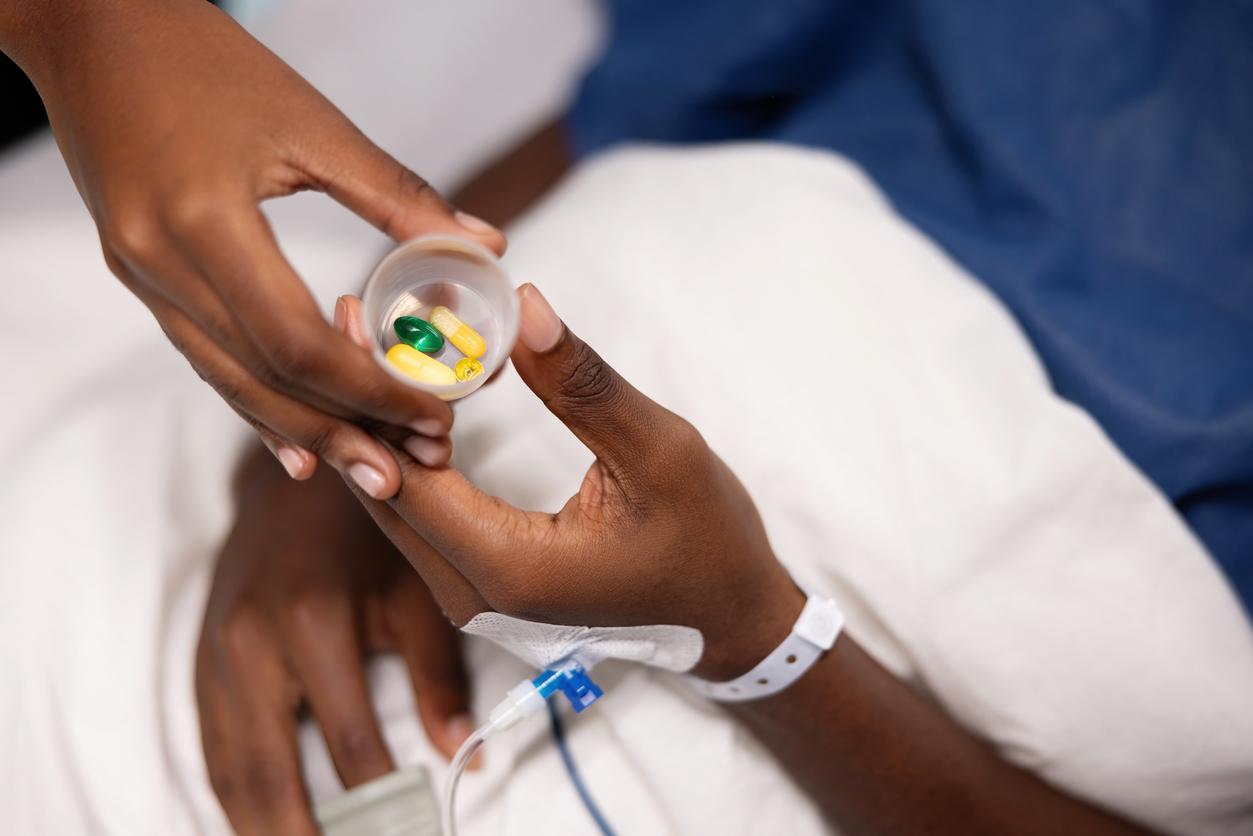 Nurse handing hospital patient a cup of pills