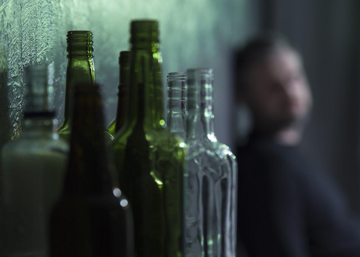 Alcoholic with empty bottle in foreground