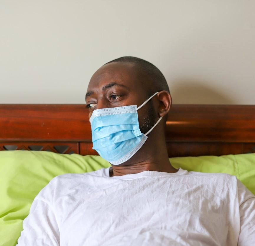 Black man wearing mask in bed