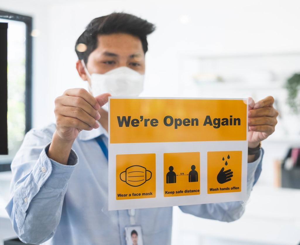 Businessman with "We're open again" sign