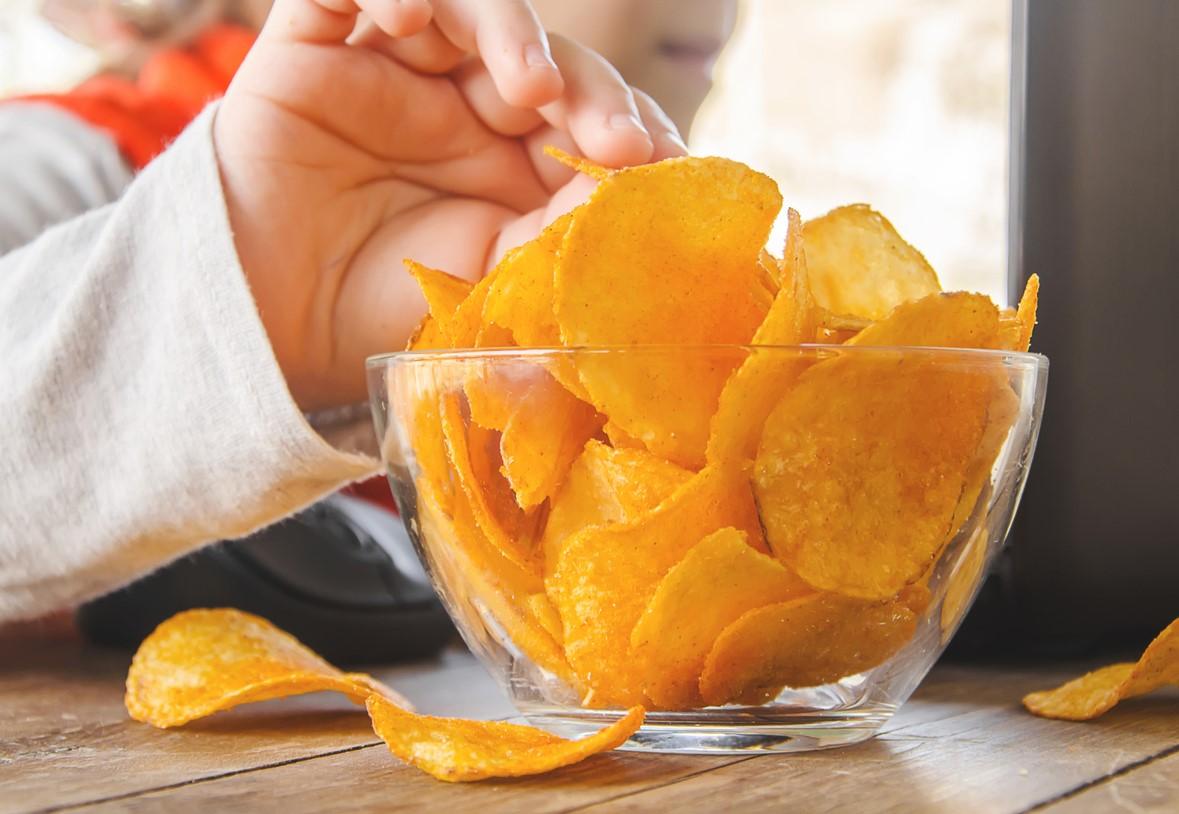 Child using computer while eating potato chips