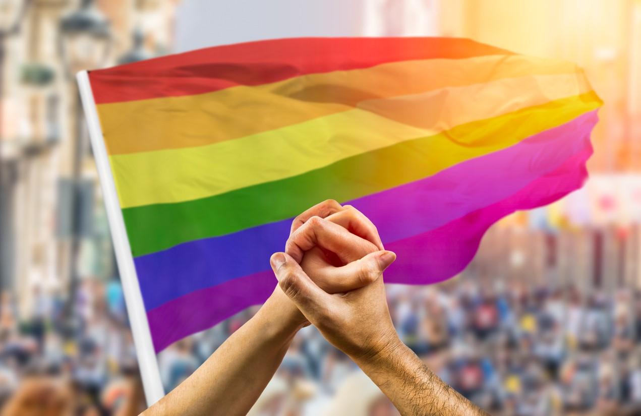 Clasped hands in front of pride flag
