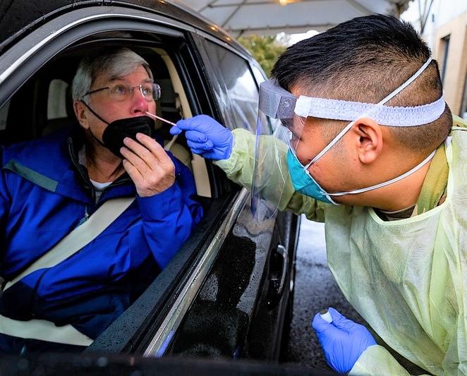 Woman in car gettnig nasal swab COVID test