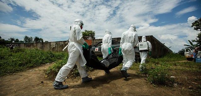 Ebola workers in Liberia carry a body bag.