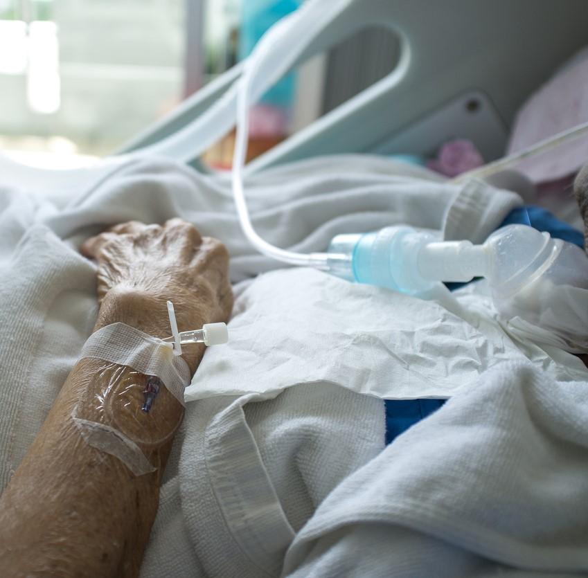 Elderly patient's hand in hospital bed