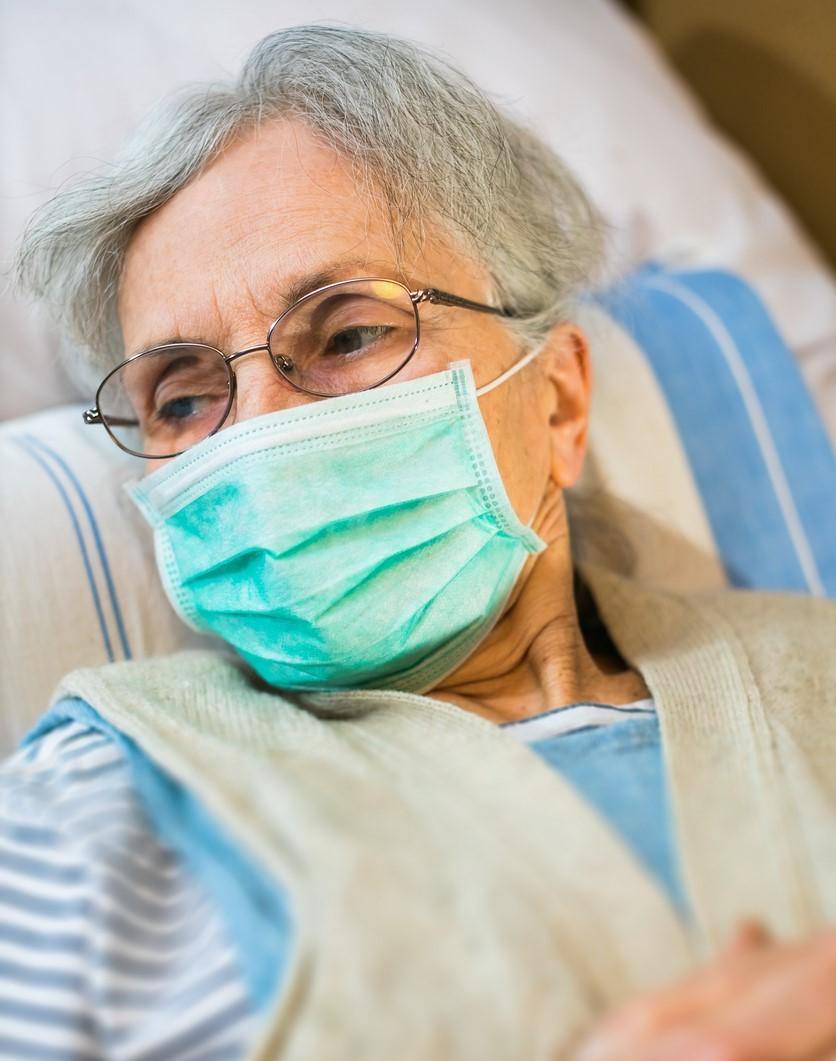 Elderly woman in bed wearing a mask