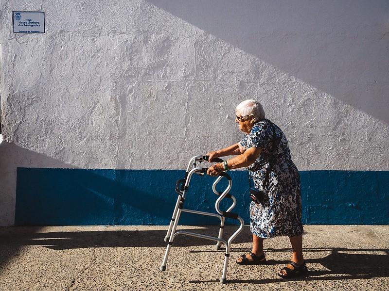 Elderly woman walking outside with walker