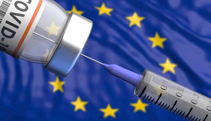 COVID vaccine vial and syringe in front of EU flag